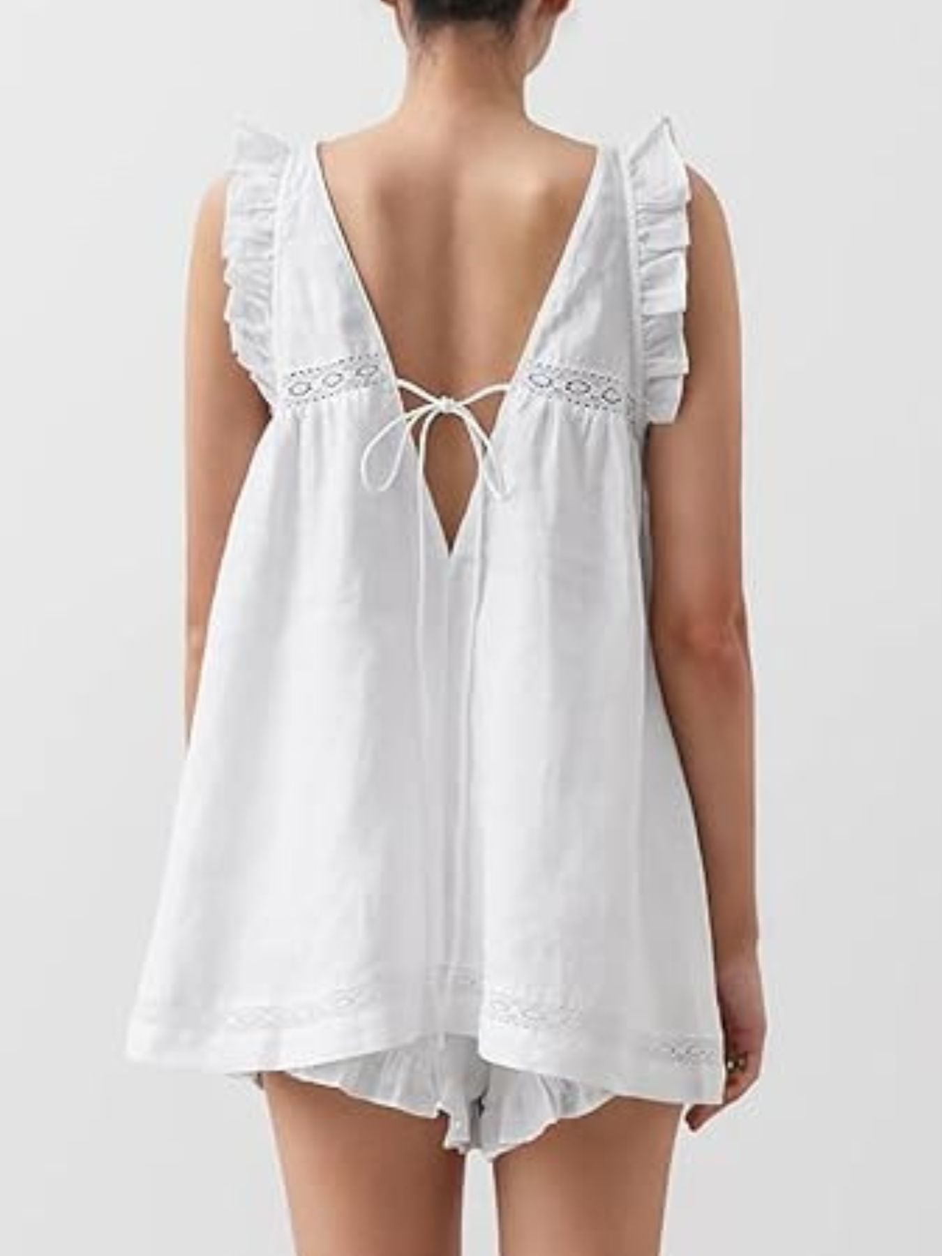 White ruffled V-neck top with lace trim and tie back, paired with ruffled shorts.