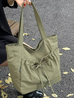 Olive green nylon tote bag with drawstring bow detail and exterior pockets