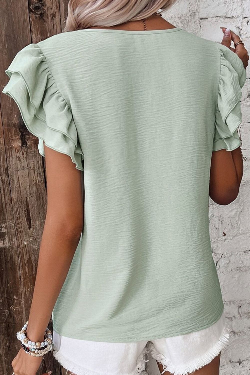 Sage flutter sleeve v-neck blouse with textured fabric.