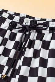 Black and white checkerboard lounge shorts with drawstring waist and gold-tipped ends.