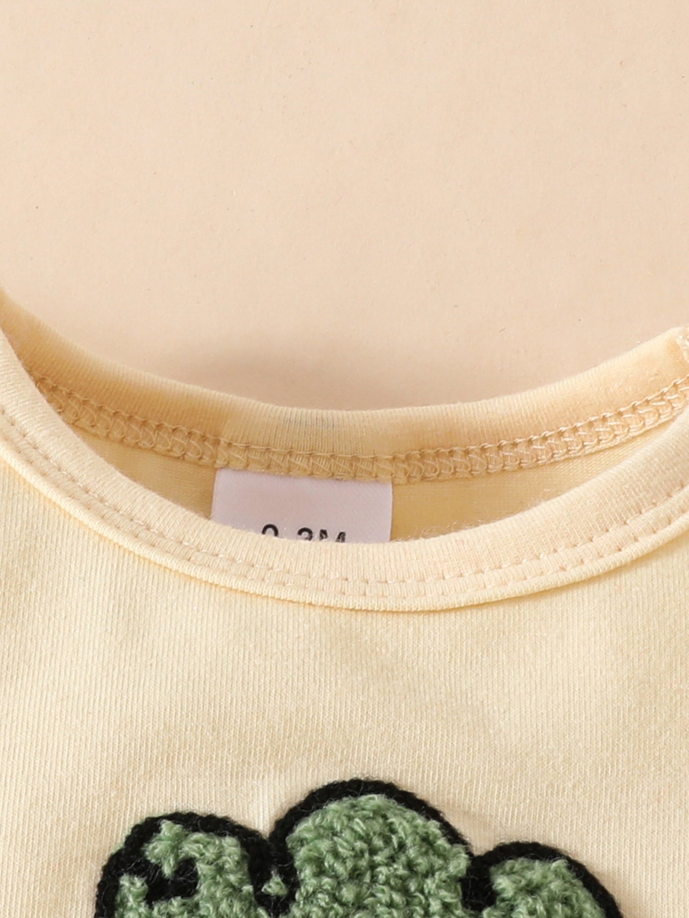 Yellow baby bodysuit with charming carrot appliqué detail and size tag