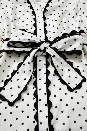 White polka dot midi dress with black scalloped trim and tie belt.