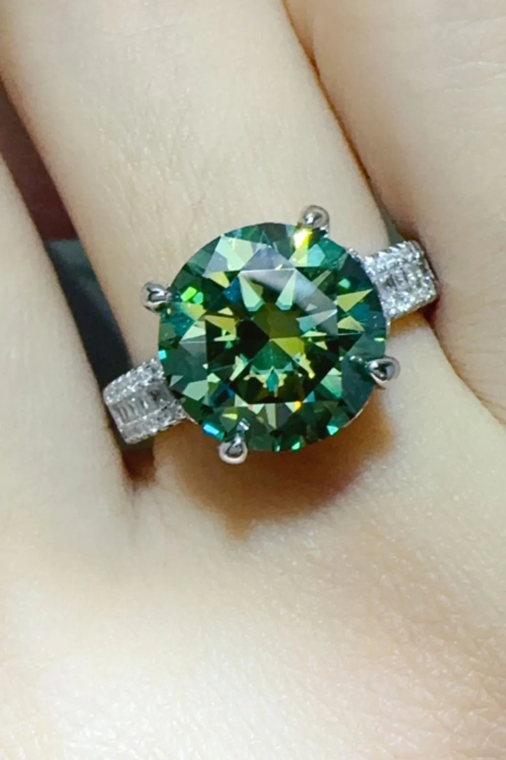 Emerald cut dark green halo engagement ring in sterling silver with baguette accents.