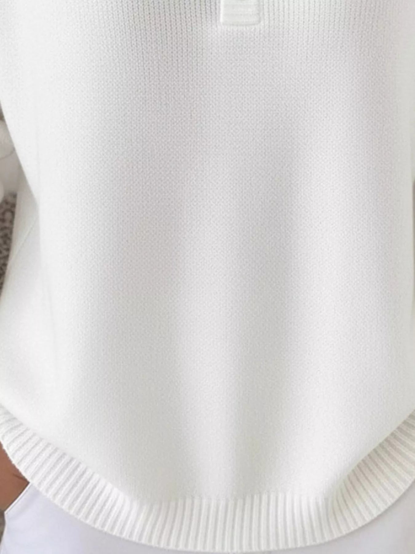 White knit top with button detail and ribbed hem