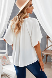 White relaxed V-neck blouse with cap sleeves and gathered neckline detail.