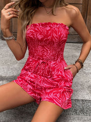 Smocked bandeau romper in strawberry print with tie waist and pockets.