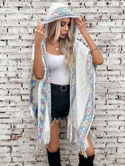 White knit hooded wrap with colorful embroidered trim and fringe detail.