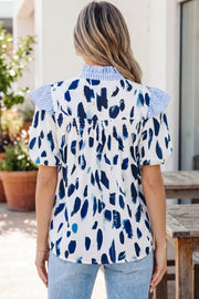 White polyester shirt with blue abstract print, ruffled collar and sleeves.