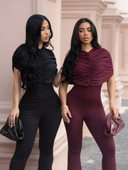 Black and burgundy ruched rompers with cap sleeves and flared legs.