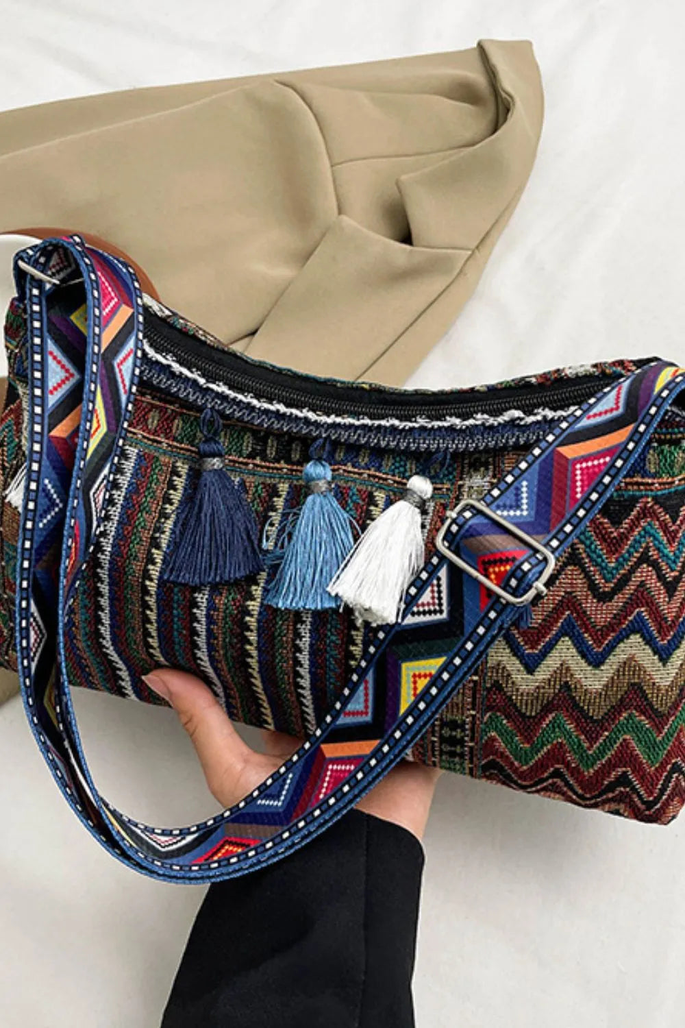 Geometric embroidered shoulder bag with colorful chevron pattern and tassels.