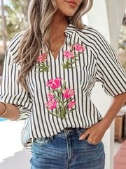 Striped V-neck blouse with bright pink floral embroidery and short sleeves.