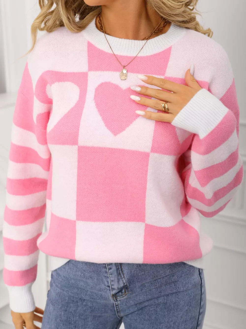 Blush pink and white checkerboard knit sweater with heart detail and striped sleeves.