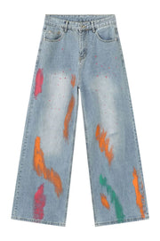 Painterly wide-leg denim jeans in light wash with abstract paint splatters and strokes in pink, orange, and green.
