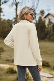 Textured knit polo shirt in ivory with a subtle cable pattern and buttoned collar.