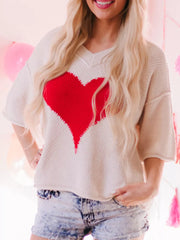 Beige V-neck knit sweater with a large red heart pattern and short sleeves.