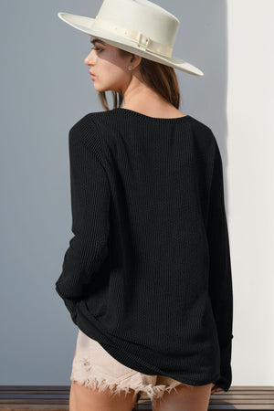 Black waffle knit henley shirt with thumbhole cuffs and a relaxed fit.