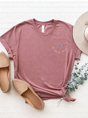 Dusty Pink graphic tee with smiley face and affirmation text, cuffed sleeves.