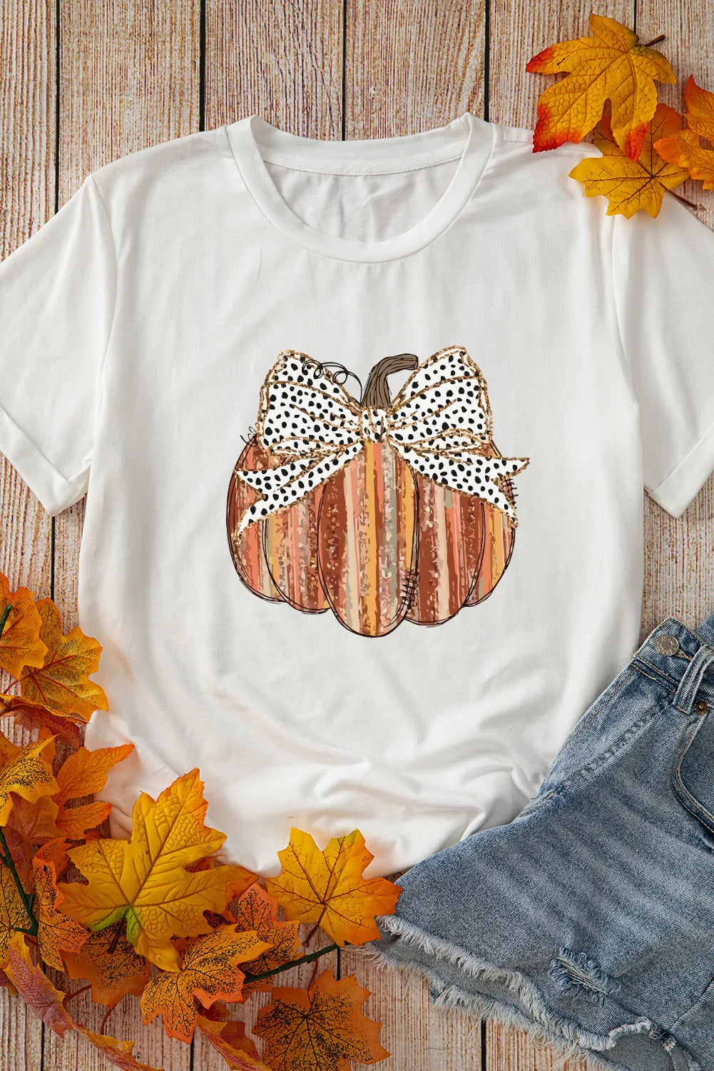 White t-shirt with striped pumpkin graphic and spotted bow detail