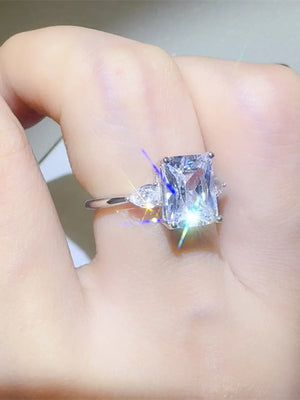 Silver ring with emerald cut center stone and pear accent stones.