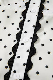 White polka dot midi dress with black scalloped trim and buttons