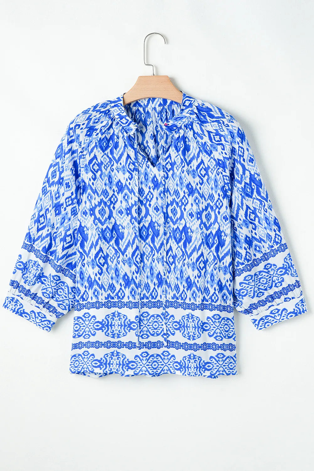 Blue ikat print V-neck blouse with border trim and 3/4 sleeves.