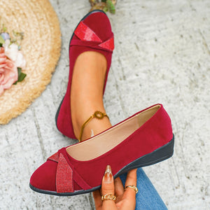 Red slip-on wedge flats with rhinestone-adorned bow detail.