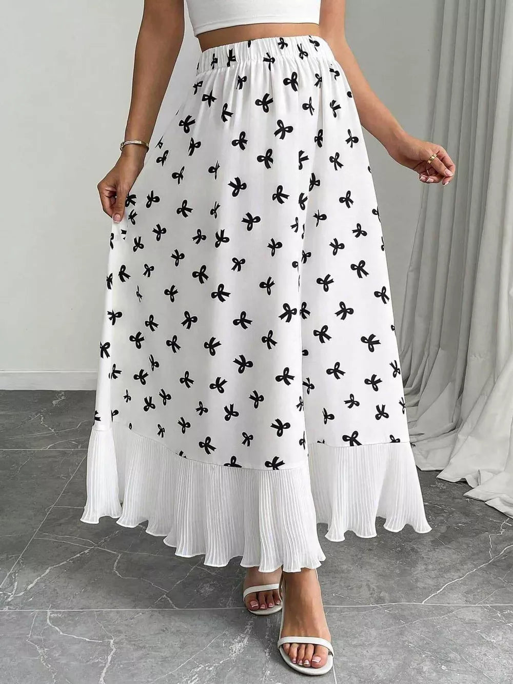 White maxi skirt with black bow print and pleated hem
