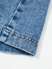 Belted denim dress detail showing stitching on blue cotton fabric.