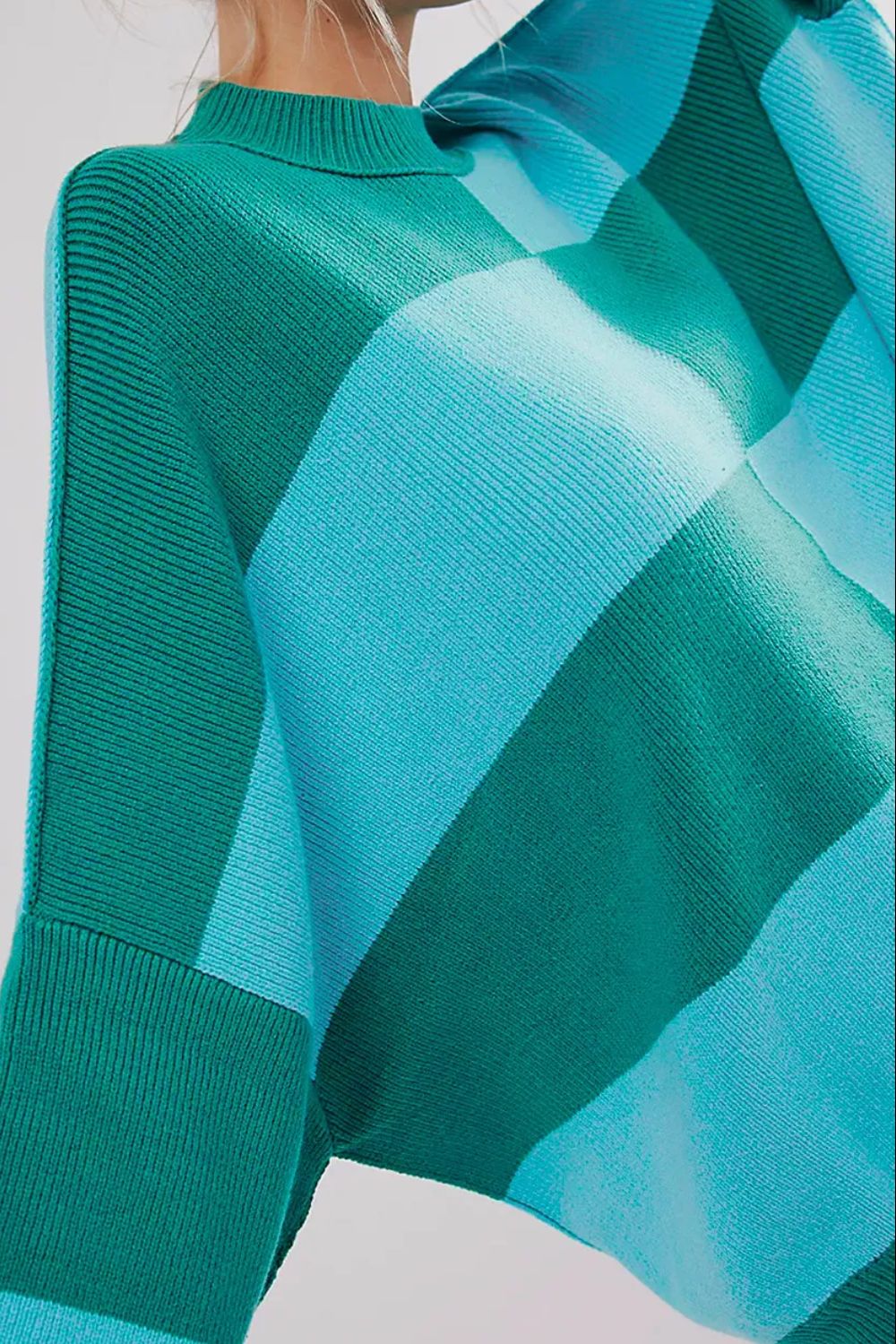 Checkerboard knit oversized sweater in turquoise and green with a mock neck and ribbed details.