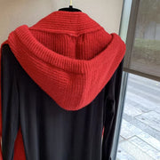 Red knit hooded scarf with a black long-sleeve top.