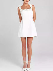 White mini dress with floral embellished square neckline and pockets.