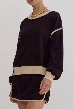 Black sweatshirt and skort set with contrast trim and crew neck, styled with a gold necklace.