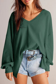 Dark green waffle knit blouson sleeve top with V-neck and cuffed sleeves.