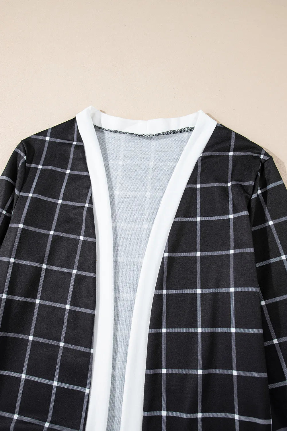 Black and white plaid duster cardigan with white trim and open front.