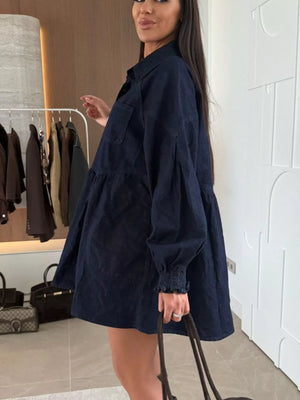 Dark blue denim mini dress with pockets, tiered skirt, and smocked cuffs.