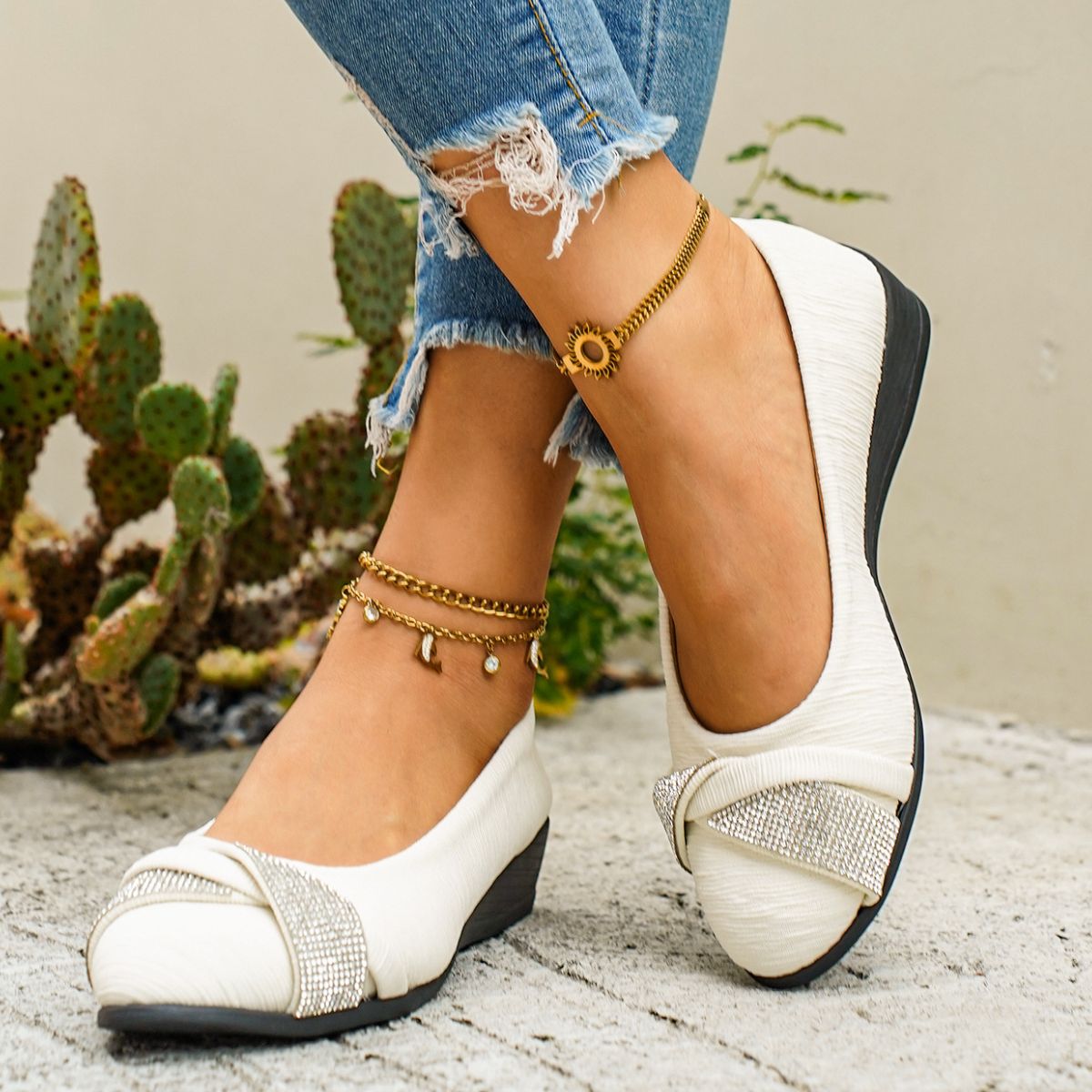 Beige slip-on wedge flats with rhinestone bow detail and textured fabric.