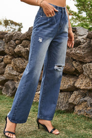 Distressed wide-leg denim trousers in medium wash with ripped details and frayed hem.