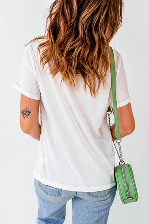 White t-shirt with rolled sleeves and a subtle eye tattoo on the arm.