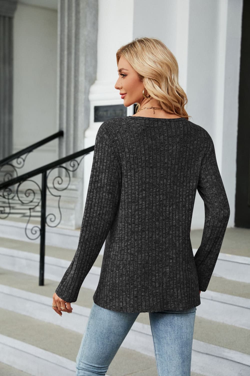 Black ribbed tunic top with button detail and asymmetric hem, long sleeves.