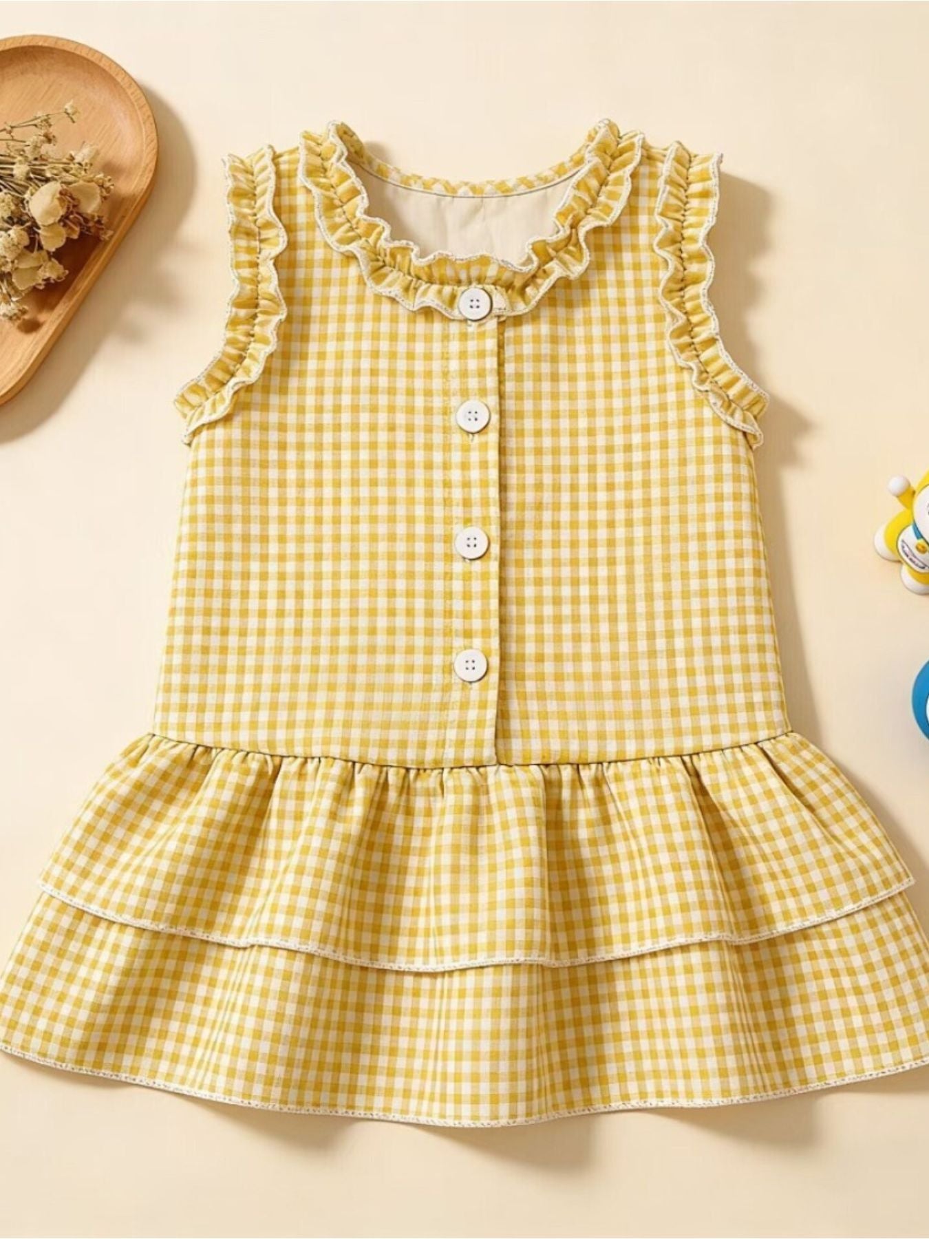 Yellow gingham baby dress with ruffled neckline and tiered skirt.