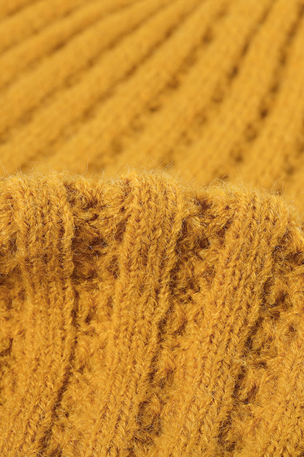 Textured ribbed knit beanie in mustard acrylic with a close-up view of the weave.