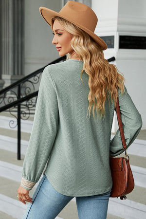 Light green textured V-neck blouse with lace trim cuffs and a relaxed fit.