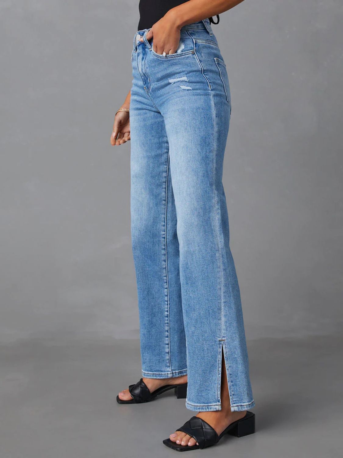Medium wash flare jeans with distressed details and side leg slits.