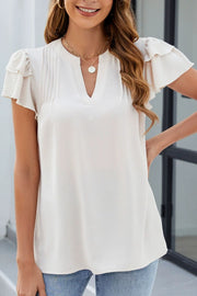 Beige blouse with pleated yoke, v-neck, and flutter sleeves.