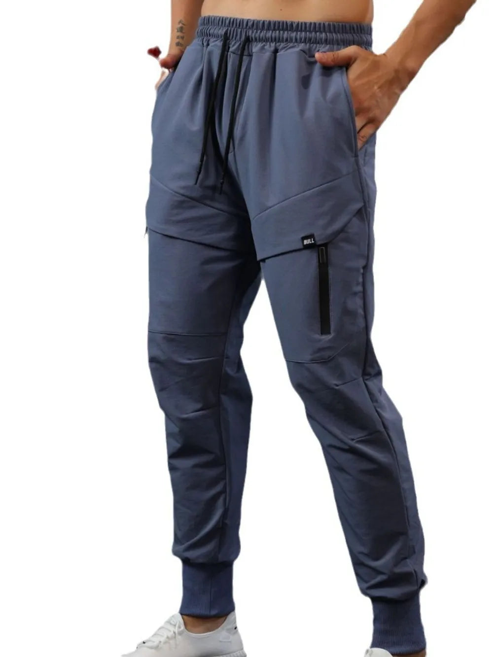 Gray technical joggers with zip pocket detail and elastic cuffs.