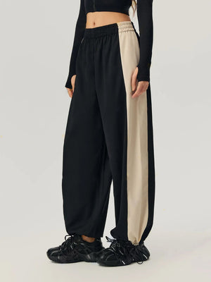Black wide-leg track pants with beige side panels and elastic waistband.