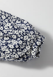 Blouse with navy and white floral print, notched sleeve detail, and cinched cuff.