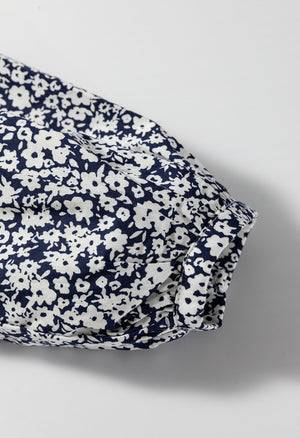 Blouse with navy and white floral print, notched sleeve detail, and cinched cuff.