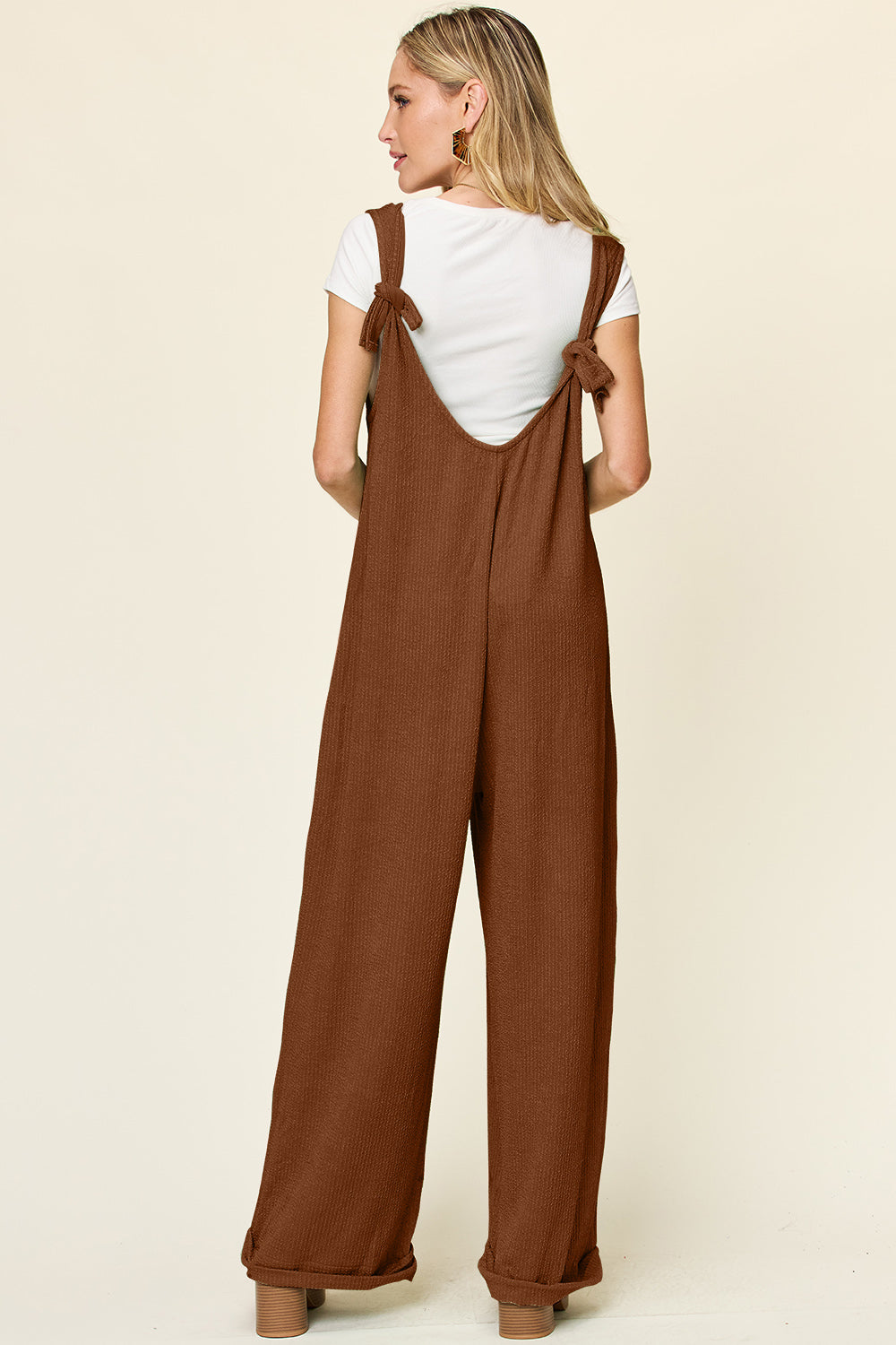Caramel ribbed knit tie-strap jumpsuit with wide legs and a white t-shirt.
