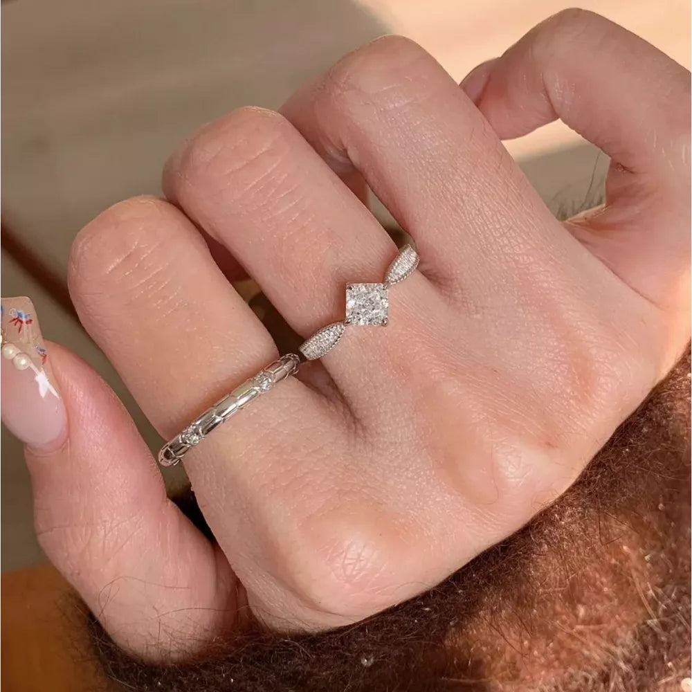 Sterling silver ring with moissanite center stone and geometric band detail.